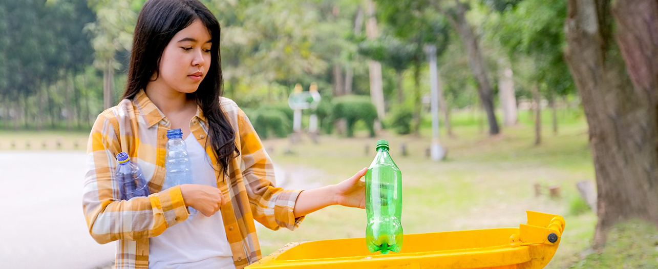A woman disposing plastic bottles in the bin